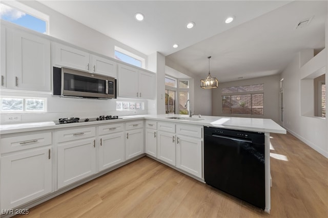 kitchen with white cabinetry, a peninsula, black appliances, and a sink