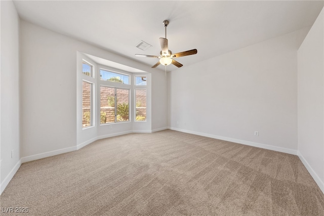 empty room featuring visible vents, light colored carpet, a ceiling fan, and baseboards