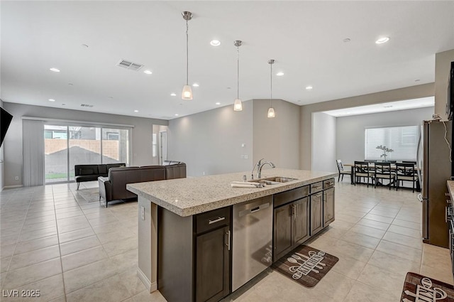 kitchen with visible vents, a center island with sink, a sink, stainless steel appliances, and dark brown cabinets