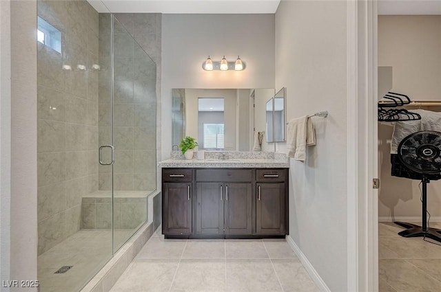 bathroom with tile patterned floors, baseboards, a stall shower, and vanity