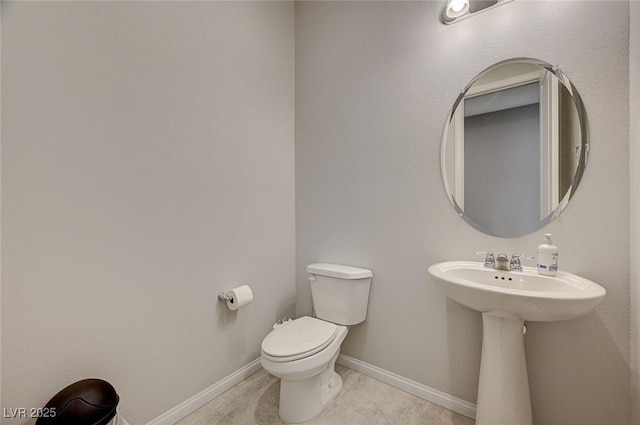 bathroom with tile patterned flooring, toilet, and baseboards