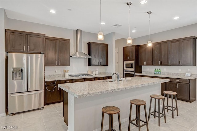 kitchen with visible vents, a sink, stainless steel appliances, dark brown cabinetry, and wall chimney exhaust hood