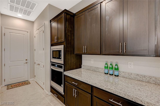 kitchen featuring visible vents, light stone countertops, dark brown cabinetry, appliances with stainless steel finishes, and light tile patterned flooring