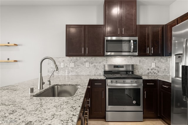 kitchen featuring decorative backsplash, light stone countertops, stainless steel appliances, and a sink