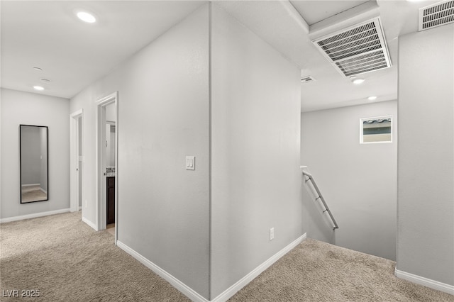 hall with an upstairs landing, visible vents, baseboards, and carpet