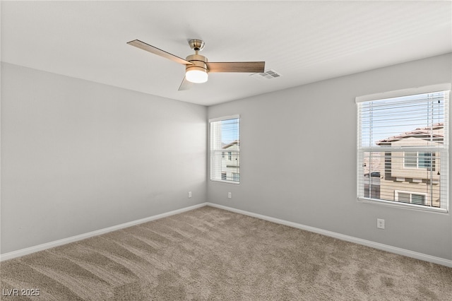 carpeted empty room featuring baseboards, visible vents, and ceiling fan