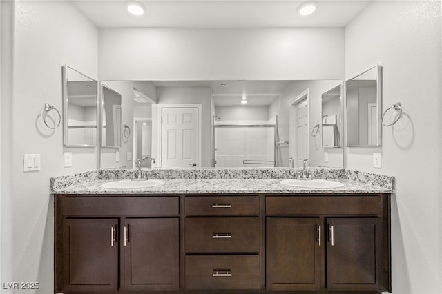 full bathroom featuring double vanity, a shower with door, and a sink