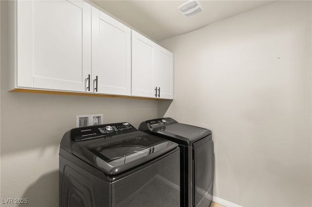 clothes washing area featuring visible vents, cabinet space, baseboards, and washing machine and clothes dryer