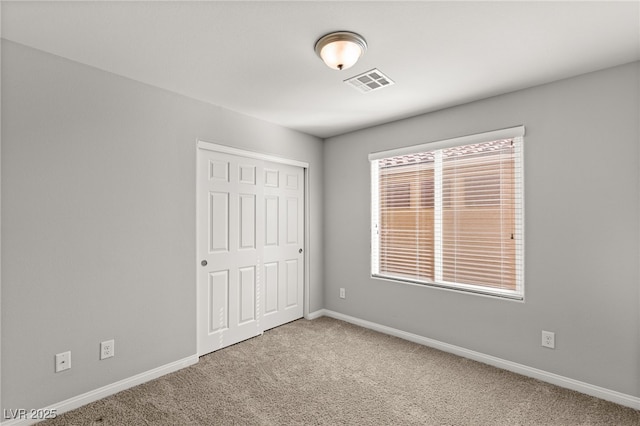 unfurnished bedroom with a closet, baseboards, visible vents, and carpet floors