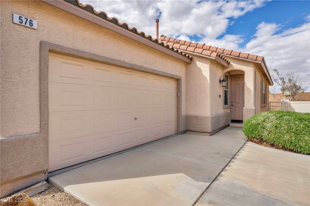 exterior space with stucco siding, fence, driveway, and a tile roof