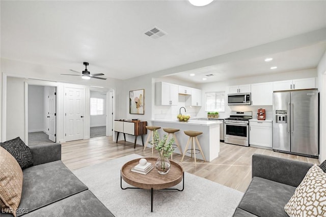 living area with recessed lighting, visible vents, ceiling fan, and light wood finished floors