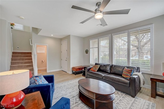 living room with visible vents, light wood-style floors, a healthy amount of sunlight, and stairway