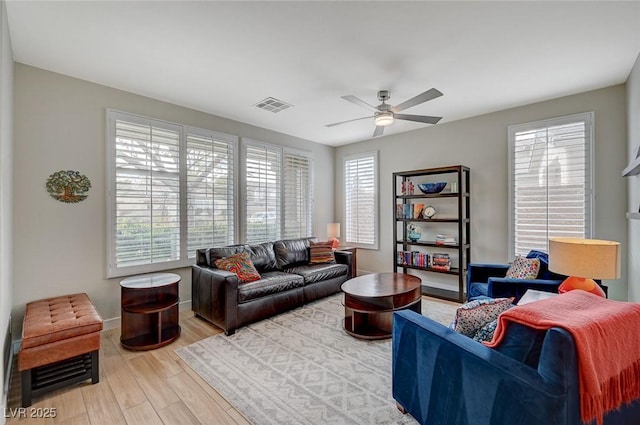 living area with light wood finished floors, visible vents, plenty of natural light, and a ceiling fan