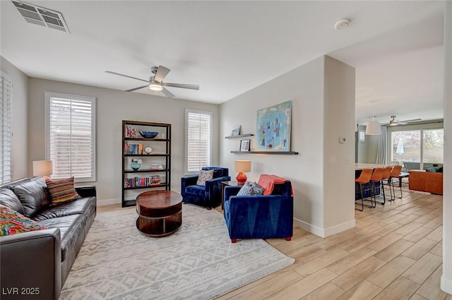 living area featuring visible vents, wood finished floors, plenty of natural light, and ceiling fan