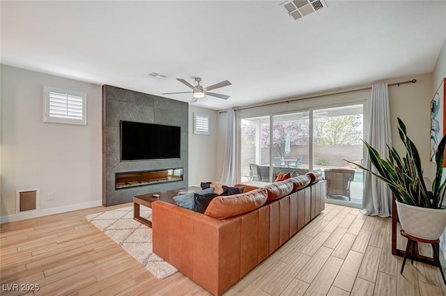 living area with baseboards, a ceiling fan, visible vents, and light wood-type flooring