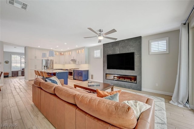 living room with visible vents, ceiling fan, baseboards, recessed lighting, and light wood-style floors