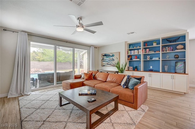 living room with visible vents, baseboards, light wood-style floors, and a ceiling fan