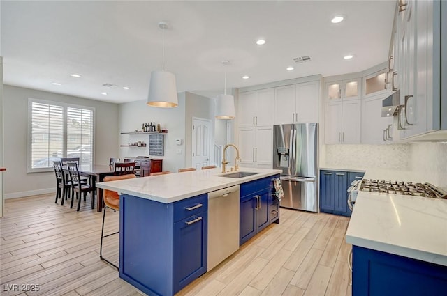 kitchen with visible vents, blue cabinetry, a sink, tasteful backsplash, and appliances with stainless steel finishes