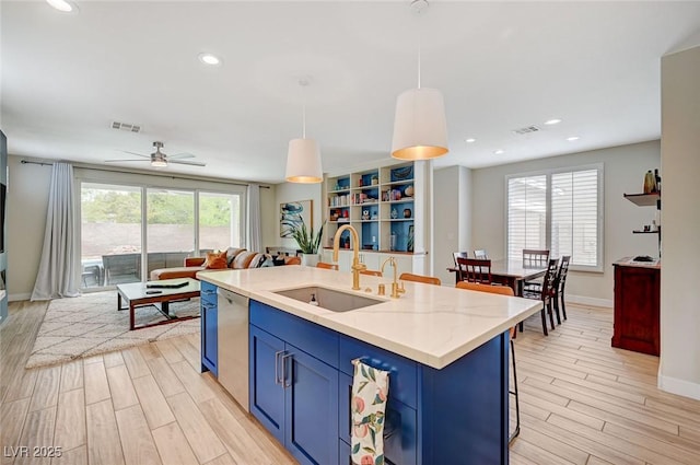 kitchen featuring light wood finished floors, visible vents, blue cabinetry, dishwasher, and a sink