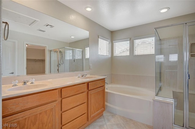 bathroom featuring visible vents, a sink, a shower stall, double vanity, and a bath