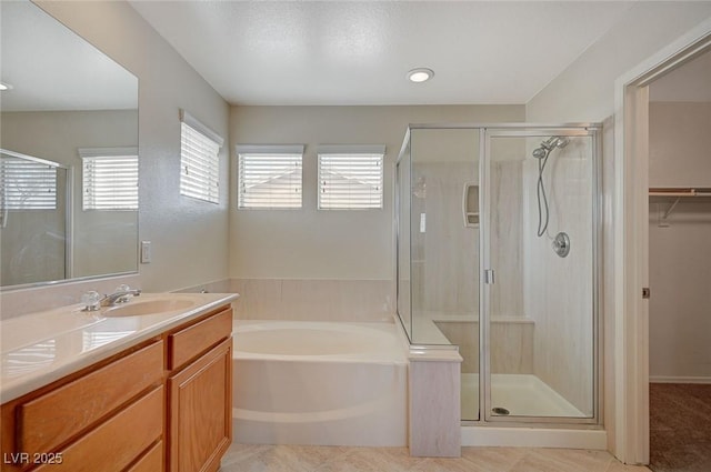 bathroom featuring a spacious closet, tile patterned floors, a stall shower, a bath, and vanity