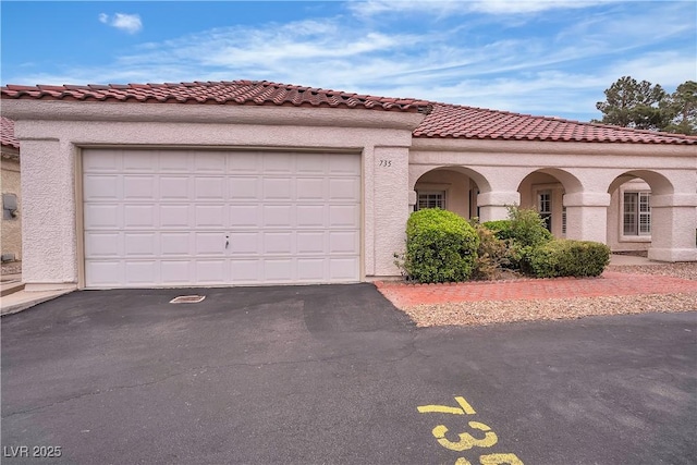 mediterranean / spanish-style house with a tile roof, stucco siding, driveway, and an attached garage