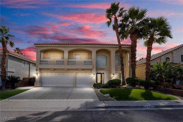 mediterranean / spanish house featuring a tiled roof, stucco siding, driveway, and an attached garage