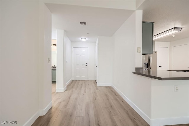 hall featuring visible vents, baseboards, and light wood-style floors