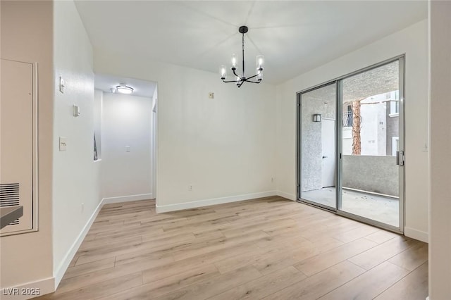 unfurnished dining area with baseboards, a notable chandelier, and light wood finished floors