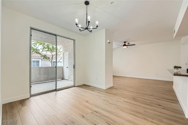 unfurnished dining area with baseboards, ceiling fan with notable chandelier, and light wood finished floors