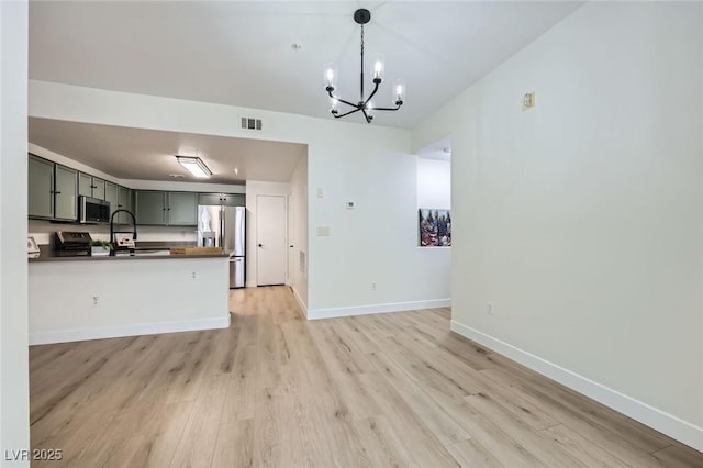 kitchen featuring visible vents, light wood-style flooring, dark countertops, stainless steel appliances, and baseboards