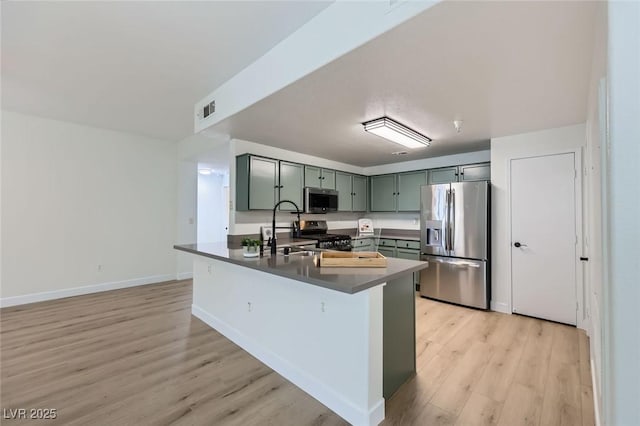 kitchen featuring visible vents, a sink, stainless steel appliances, green cabinets, and dark countertops