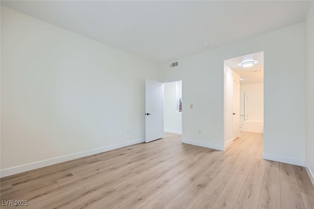 empty room featuring visible vents, baseboards, and light wood finished floors