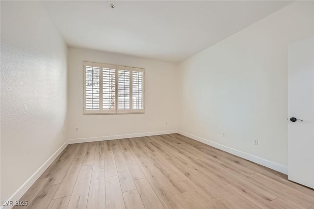 unfurnished room with baseboards and light wood-style floors