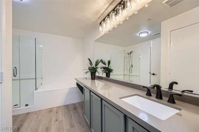 bathroom featuring vanity, wood finished floors, visible vents, a shower stall, and a bath