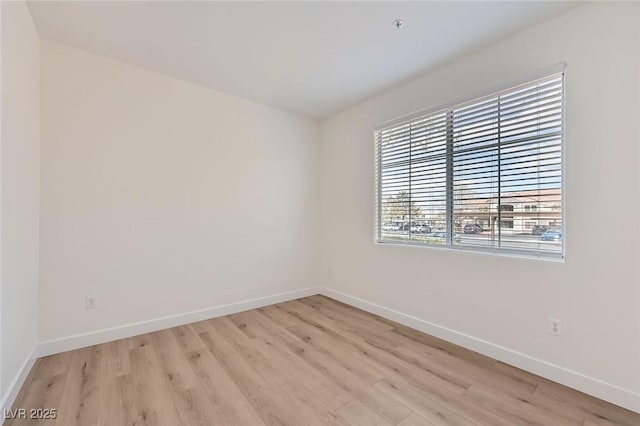 spare room with baseboards and light wood-style floors