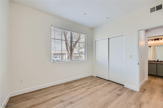 unfurnished bedroom featuring light wood finished floors, visible vents, baseboards, a closet, and a sink