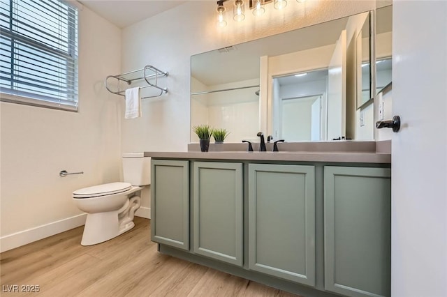 bathroom with vanity, toilet, wood finished floors, and baseboards