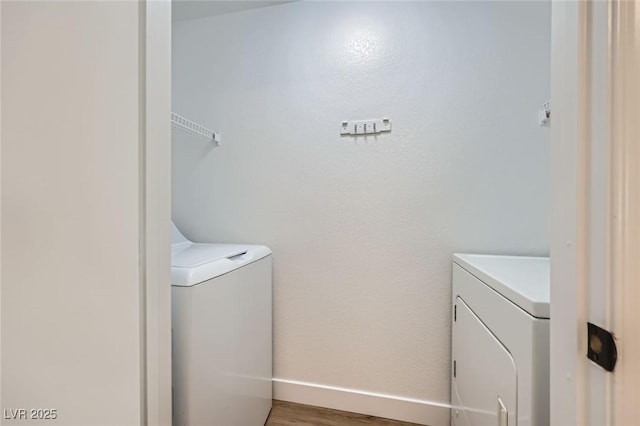 washroom with washer and dryer, laundry area, baseboards, and light wood finished floors