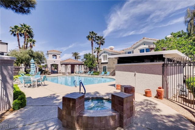 community pool featuring a community hot tub, a patio, and fence