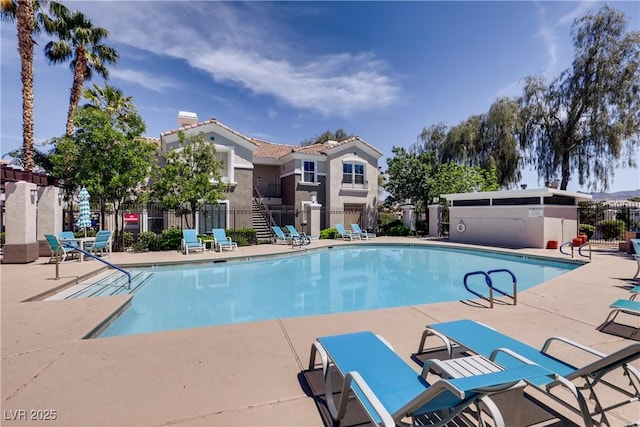 community pool with a patio area and fence