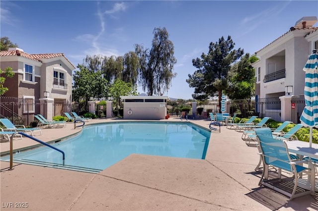 community pool with a patio area and fence