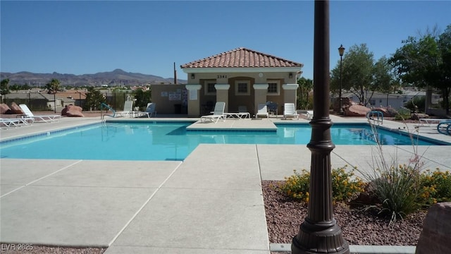 pool with an outbuilding, a mountain view, a patio, and fence