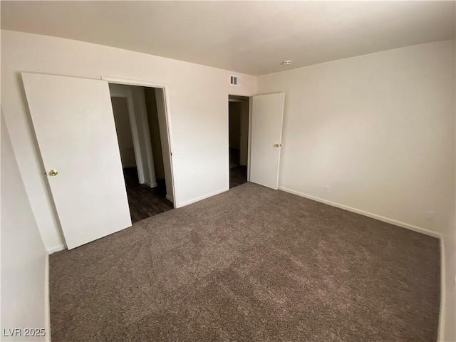 unfurnished bedroom with visible vents, dark colored carpet, and baseboards