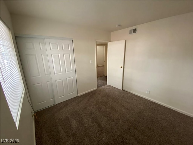 unfurnished bedroom with a closet, carpet flooring, baseboards, and visible vents