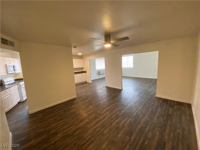 unfurnished living room featuring visible vents, baseboards, dark wood finished floors, and a ceiling fan