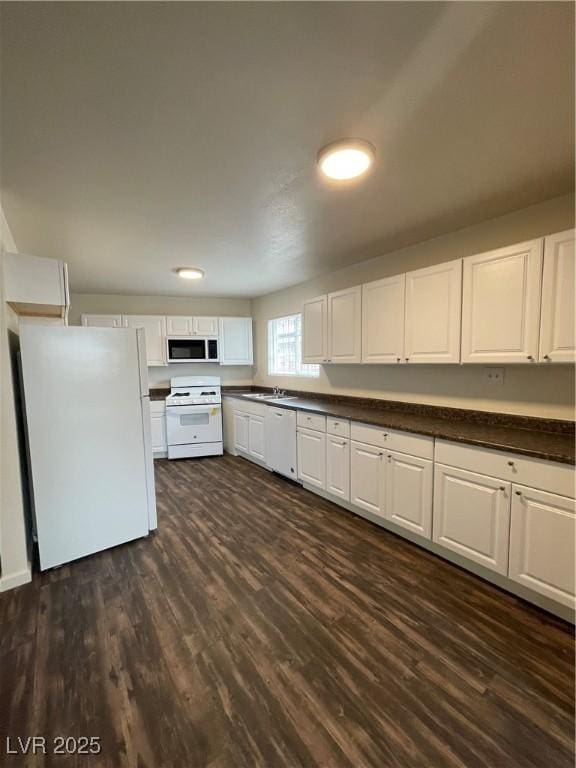 kitchen with dark countertops, white cabinets, white appliances, and dark wood-style flooring