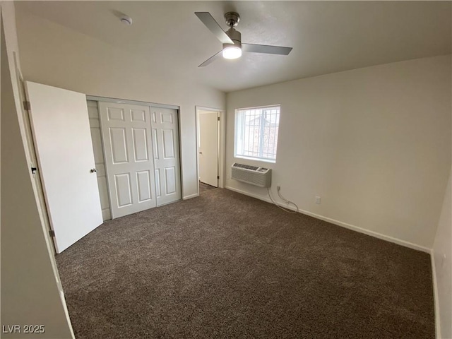 unfurnished bedroom with an AC wall unit, a closet, dark colored carpet, baseboards, and ceiling fan