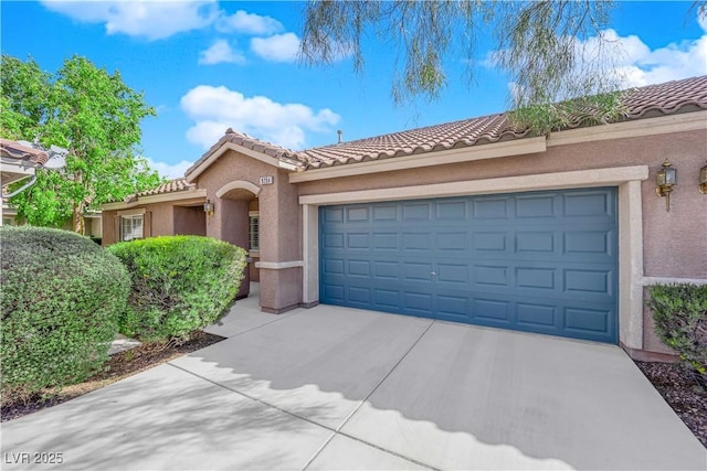 mediterranean / spanish house featuring stucco siding, driveway, a tile roof, and an attached garage