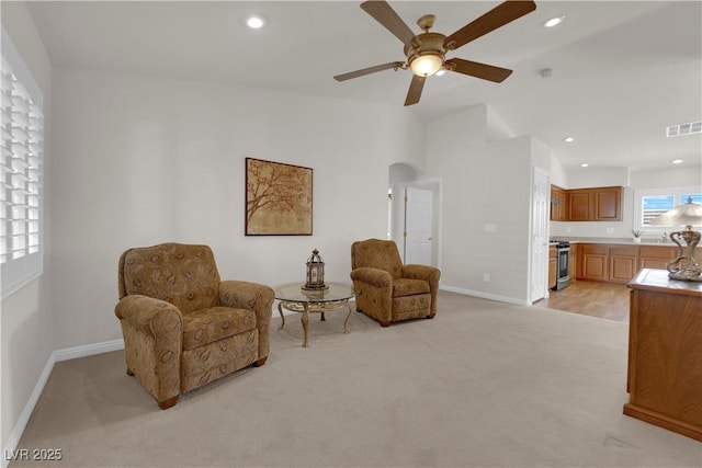 living area featuring visible vents, baseboards, light carpet, recessed lighting, and arched walkways